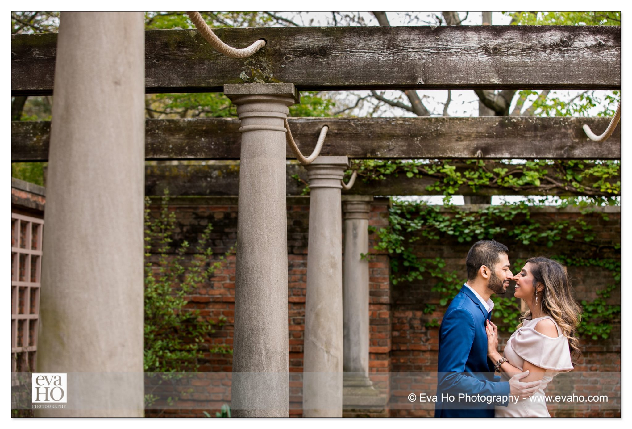 Couple snuggle under the beautiful Roman structure inside the Rose Garden at the Chicago Botanic Garden.